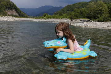 happy laughing girl enjoying swimming in river with rubber ring crocodile