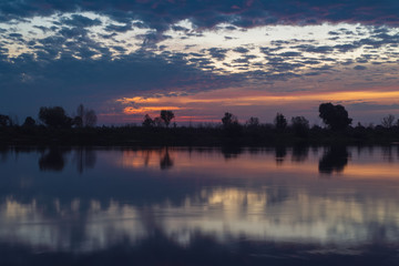 Summer landscape of Belarus. Beautiful sunrise over the Pripyat river. Reflections of clouds on the water.