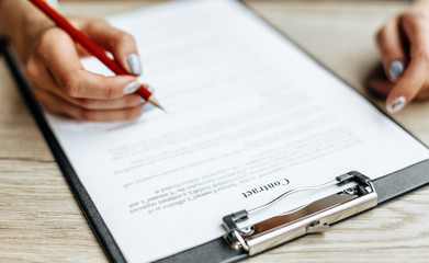 Young girl office worker or business lady signs documents. Concentrated businesswoman working with papers. Business concept