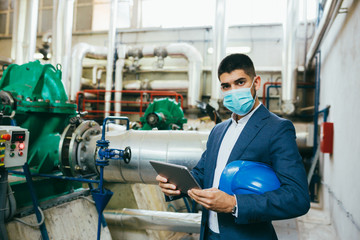 businessman holding tablet computer in industry plant, wearing face mask, covid