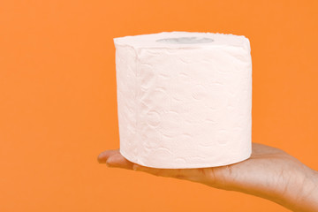 A roll of toilet paper in a woman's hand on a yellow background