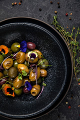 different types of olives on a dark concrete