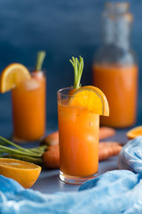 Fresh orange and carrot juice on blue background.