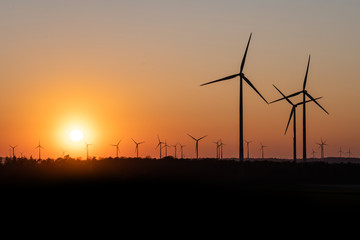 Black Silhouette of windturbines energy generator on amazing sunset at a wind farm in germany