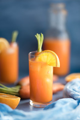 Fresh orange and carrot juice on blue background.