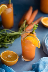 Fresh orange and carrot juice on blue background.