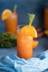 Fresh orange and carrot juice on blue background.