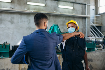 middle aged industry worker and businessman handshake indoor in heating plant, covid protected with face masks