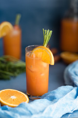 Fresh orange and carrot juice on blue background.