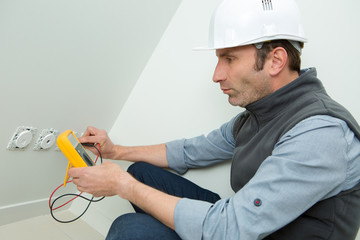 mature man testing socket with multimeter