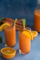 Fresh orange and carrot juice on blue background.