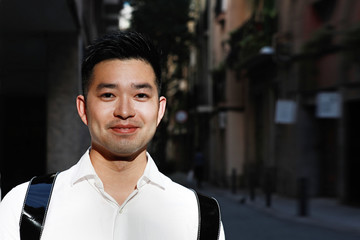 Fototapeta premium Portrait of happy young Chineese man posing on the street with smile on his face. Lifestyle concept.