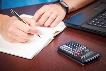 male person making calculation and writing to notebook. financial accounting concept