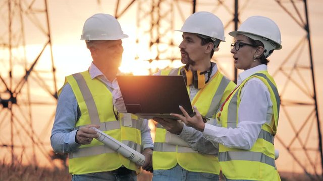 Energy saving, energy efficiency concept. Group of power engineers are having a discussion at sunset