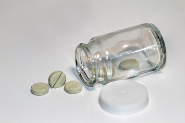 verschiedene Tabletten, Kabseln fallen aus einer Glasflasche