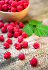 Fresh ripe red raspberries with leaves in a bowl on rustic old wooden table. Healthy organic food, summer vitamins, BIO viands, natural background. Copy space for your advertising text message