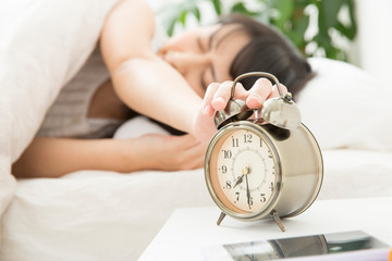 目覚まし時計を止める女性