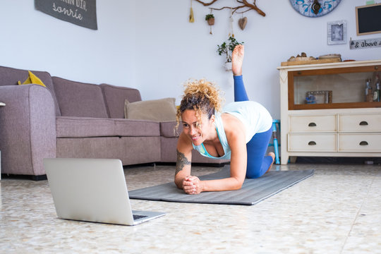 one young and beautiful woman doing exercise like yoga or workout at home alone following a tutorial looking a video on her laptop or computer pc - active people i quarantine