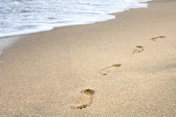 Steps in the sand with sea waves