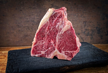 Rohes dry aged Wagyu Porterhouse Steak Block vom Rind angeboten als close-up auf einem schwarzen...