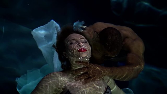 black man is pulling young beautiful woman into depth, underwater, drowning lady