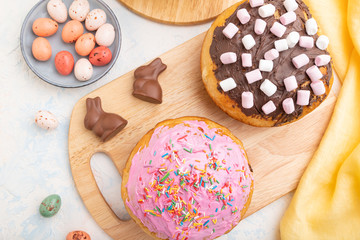 Homemade glazed and decorated easter pies with chocolate eggs and rabbits on a white concrete background. top view, close up.