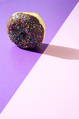 Donut with chocolate icing, on top of colorful background, with available copy space.