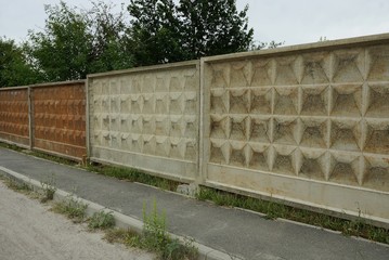 long gray brown concrete fence wall outdoors by asphalt road