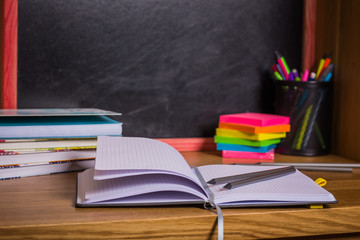 School equipment on desk on blackboard background.