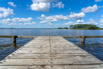 A wooden jetty made of planks sits above the water of a lake