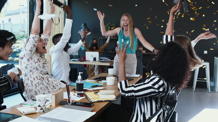 COVID-19 is over. Happy multiethnic business people team take masks off, celebrate normal life with confetti at office.