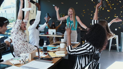 Obraz premium COVID-19 is over. Happy multiethnic business people team take masks off, celebrate normal life with confetti at office.
