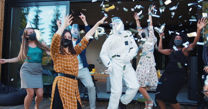 Epic Fun Party Celebration After COVID-19 Lockdown. Friends Dancing In Costumes And Masks Under Confetti Slow Motion.