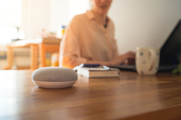 Smart ai voice speaker with woman in background.