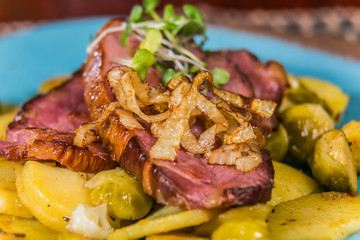 Slice of pork meat with fried onion and potatoes. The food in the restaurant. Food styling and restaurant meal serving.