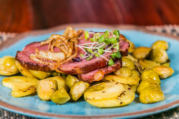 Slice of pork meat with fried onion and potatoes. The food in the restaurant. Food styling and restaurant meal serving.