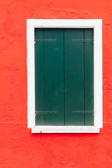 Obraz na płótnie Canvas Island of Burano, Venice, Italy. Nice window on a red and white wall. Beautiful facade. Postcard from Burano, Venice.