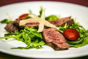 Slices of pork meat with cheese and vegetables on plates. The food in the restaurant. Food styling and restaurant meal serving.
