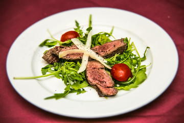 Slices of pork meat with cheese and vegetables on plates. The food in the restaurant. Food styling and restaurant meal serving.