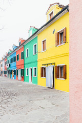 Fototapeta na wymiar Island of Burano, Venice, Italy. Colored houses. Postcard from Burano on foggy day. Vertical image.
