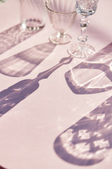 Beautiful shadows from crystal glasses of various shapes. Shadows on a pink background