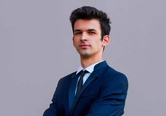 Happy smiling businessman with crossed arms pose, with blank copyspace area for text or slogan, against gray background