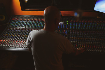 Music producer controlling sound mixer in music studio