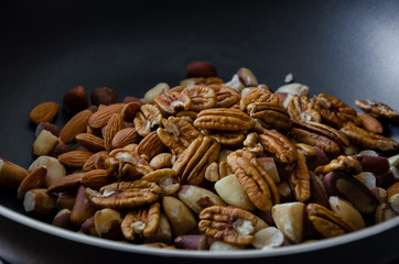 close up on a pan full of different kinds of nuts, pecan, almond, chestnut