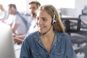 How can I help you? Beautiful call center workers in headphones are working at modern office.