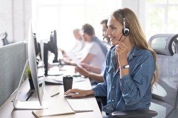 How can I help you? Beautiful call center workers in headphones are working at modern office.