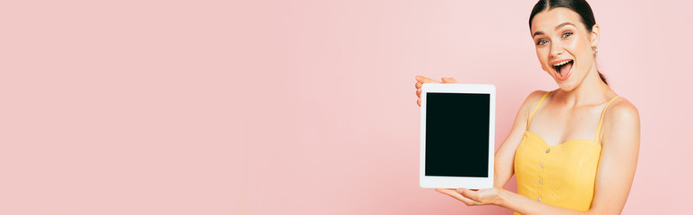 excited brunette young woman presenting digital tablet with blank screen isolated on pink, panoramic shot