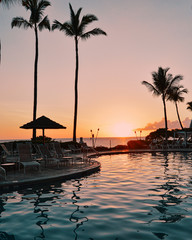 Summer sunset by the pool in Kona, Hawaii with a beautiful reflection of palm trees into the pool water