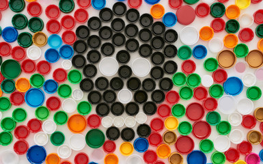 Flatlay collage with colorful plastic bottle caps and skull made of black caps on white background. Stop plastic pollution concept
