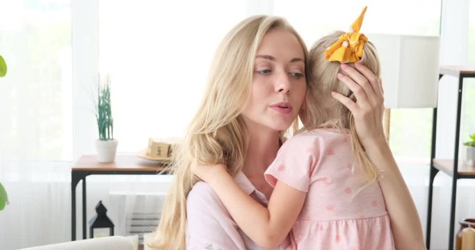 Loving mother gently stroking her little daughter at home
